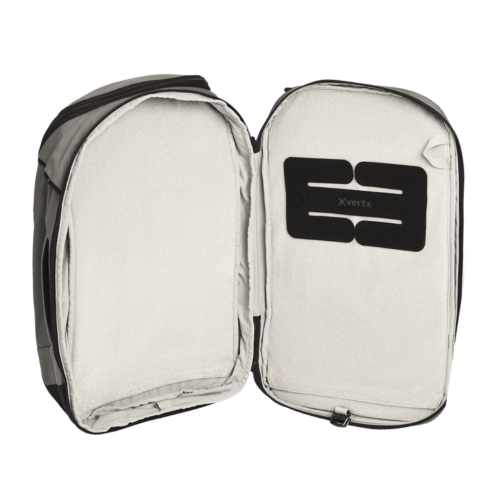 A Vertx Gamut 22L Sling backpack by Vertx is fully unzipped, revealing a spacious, light-colored interior with a black "Vertx" patch. The travel-friendly design includes a dedicated CCW compartment. No items are inside the backpack.