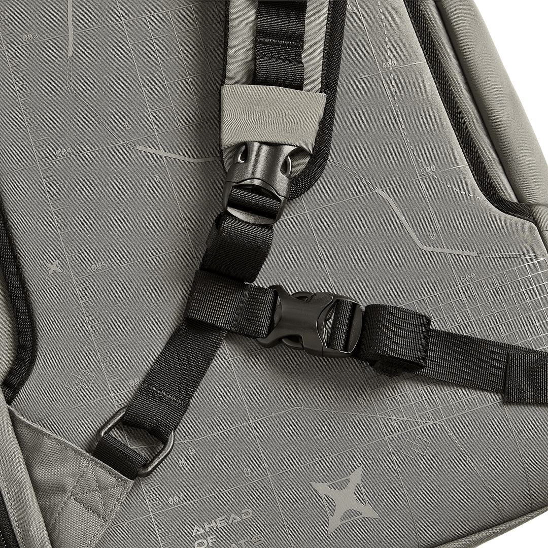 Close-up of the Vertx Gamut 22L Sling by Vertx, a gray, travel-friendly backpack with black adjustable straps, a plastic buckle, and fabric featuring white geometric patterns and the text "AHEAD OF WHAT’S POSSIBLE.
