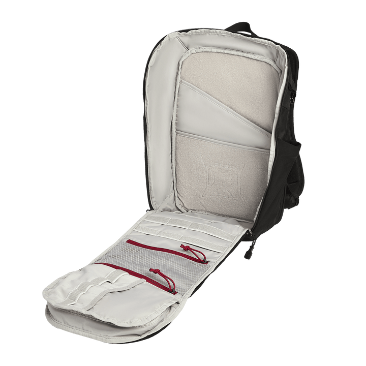 The Vertx Gamut 22L Pack by Vertx is shown fully unzipped, revealing a light gray interior with multiple compartments, mesh pockets, and red zipper pulls. Its rapid access design ensures effortless organization, set against a plain white background.