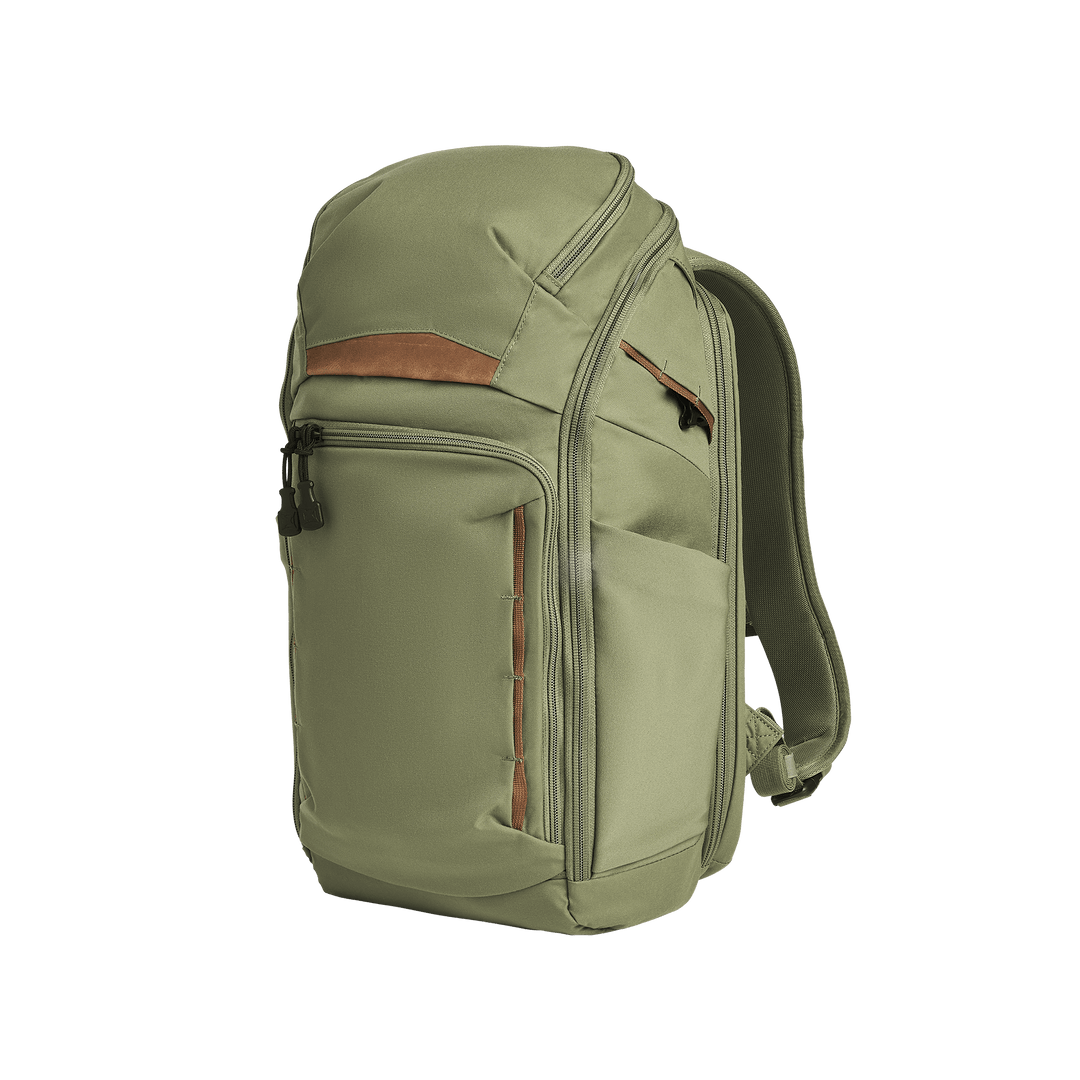 The Vertx Gamut 22L Pack in Evergreen features a zippered top compartment, front zipper pocket, brown accent strip, two side pockets, rapid access CCW compartment, and adjustable shoulder straps, shown on a white background.