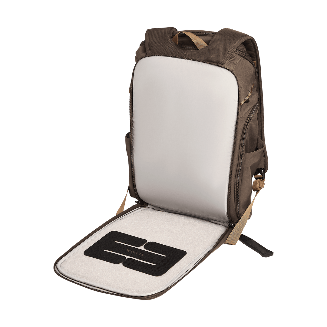 The Vertx Gamut 26L Pack by Vertx is shown open, revealing a light gray interior with an inner compartment, CCW compartment, and an organized flat pocket on the inside front flap. The backpack’s straps and sides are also visible.