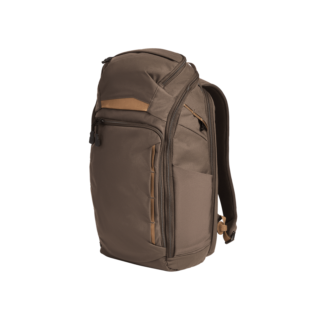 The Vertx Gamut 26L Pack by Vertx, in brown and tan, features multiple zippered compartments, a rapid access CCW pocket, and padded shoulder straps, displayed standing upright against a plain white background.