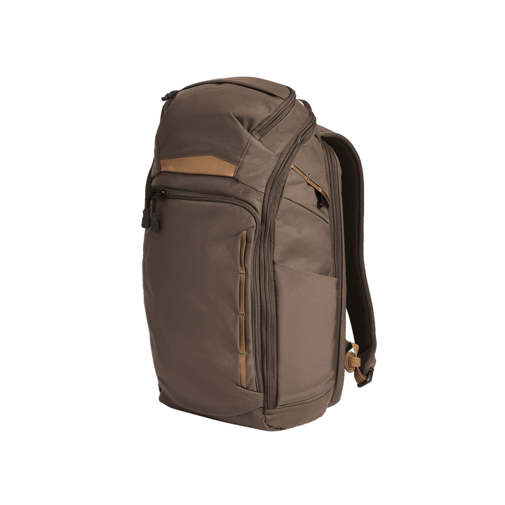 The Vertx Gamut 26L Pack by Vertx, in brown and tan, features multiple zippered compartments, a rapid access CCW pocket, and padded shoulder straps, displayed standing upright against a plain white background.