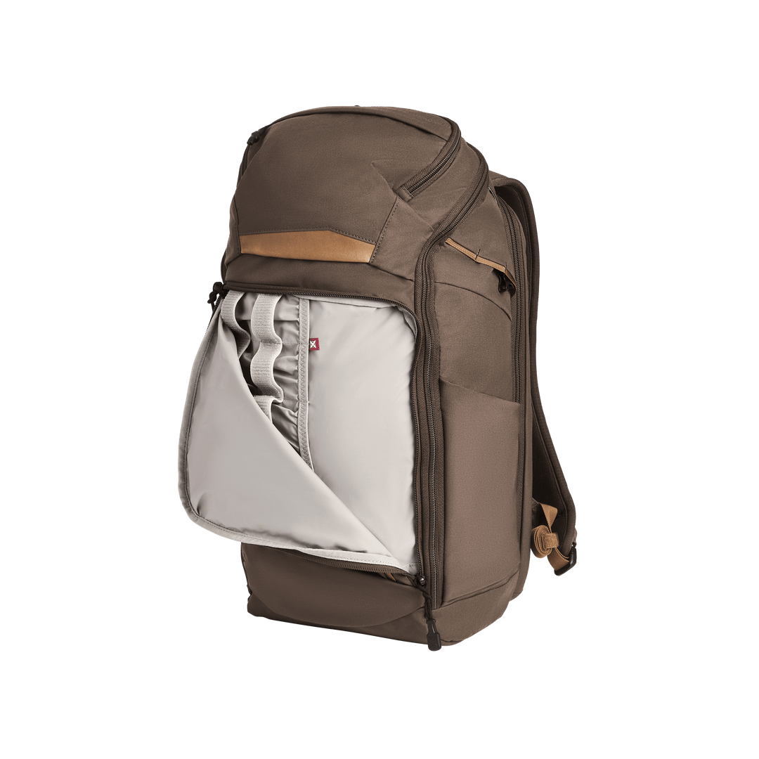 The Vertx Gamut 26L Pack by Vertx is a brown EDC backpack with a top handle and shoulder straps, shown upright. Its unzipped front pocket reveals padded compartments, slots, and a Rapid Access Pull for organized storage.