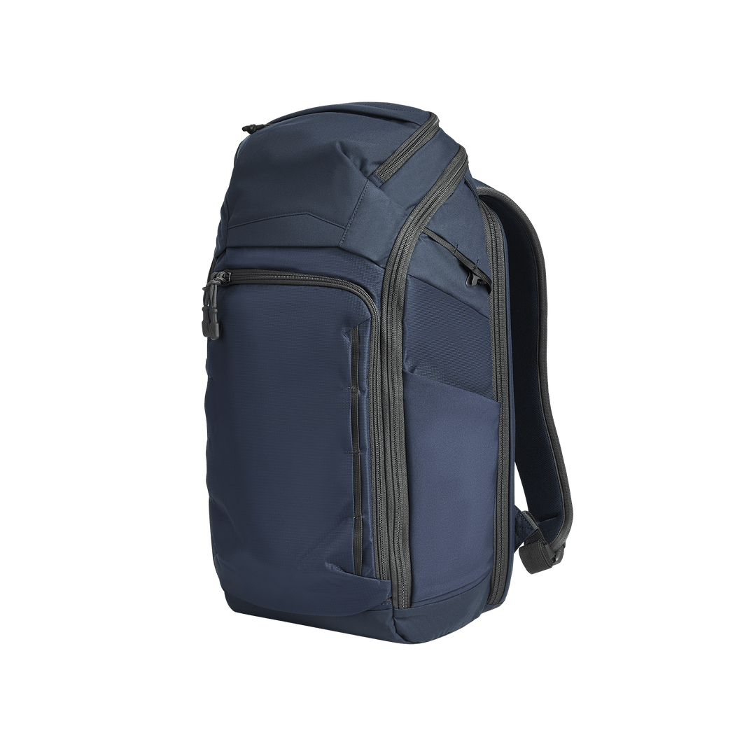 The Vertx Gamut 26L Pack by Vertx is a dark blue EDC backpack with multiple zippered compartments, a rapid access CCW compartment, and black padded shoulder straps, shown against a plain white background.