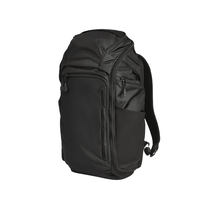 The Vertx Gamut 32L Pack by Vertx is a black travel backpack featuring multiple zippered compartments, side pockets, and padded shoulder straps, pictured standing upright against a plain white background.