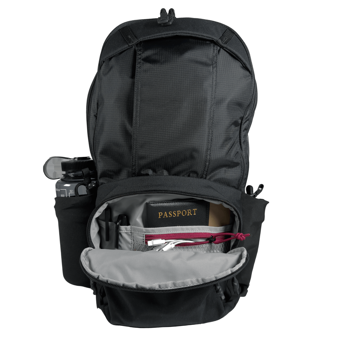 The Vertx Ready Pack X by Vertx is shown open, displaying an organized interior with a passport, camera on the side, pen, and small accessories in pockets. The main flap is unzipped for rapid access to your essentials.