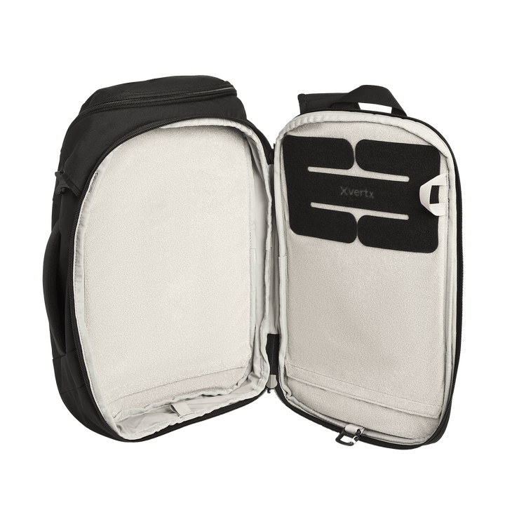 The Vertx Gamut 18L Sling by Vertx is shown open, featuring a spacious, light-colored interior with a rectangular padded section labeled "Vertx" and a dedicated CCW compartment for rapid access inside the top flap.