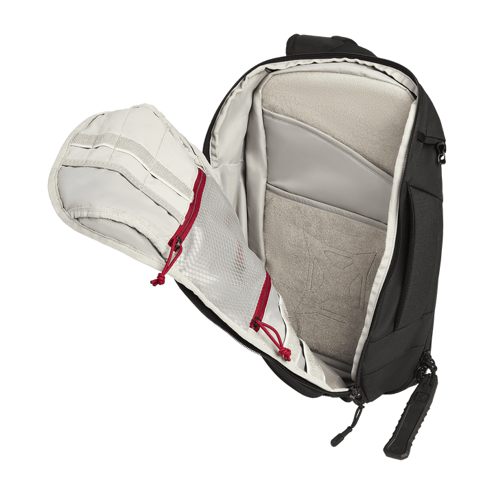 The Vertx Gamut 18L Sling by Vertx is shown open, displaying a padded compartment, beige interior lining, and two mesh zippered pockets with red pulls on the inside of the flap for quick access.