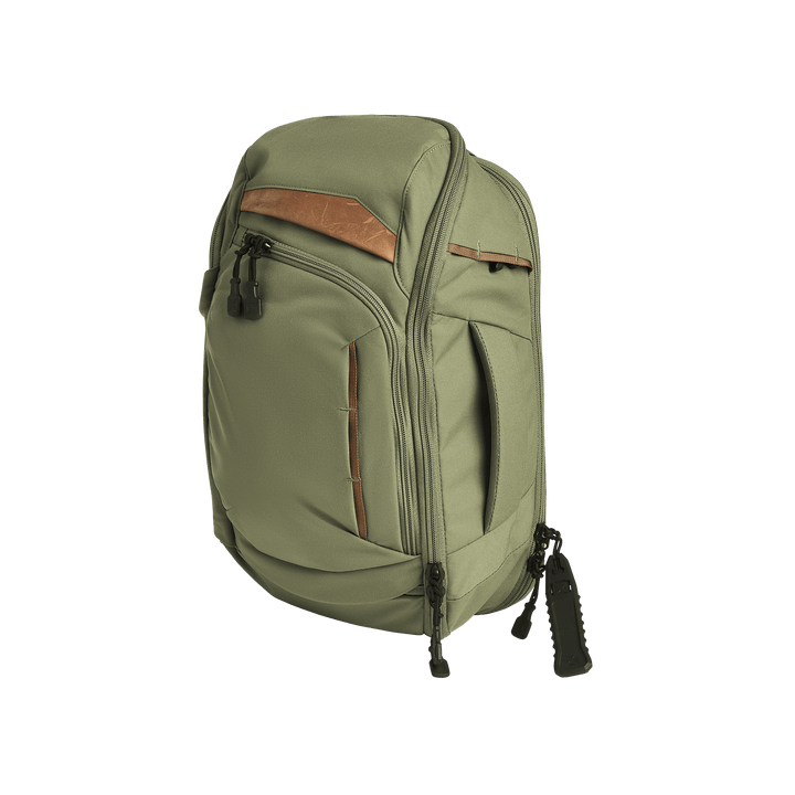 The Vertx Gamut 18L Sling by Vertx, a green backpack with brown accents and black zipper pulls, stands upright against a plain white background, showcasing multiple zippered compartments including a rapid access CCW compartment.