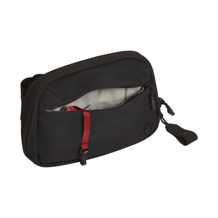 The Vertx Everyday Fanny Pack 2.1 is a compact black EDC waist pack featuring a zippered front pocket with a light gray lining, red key strap, and a black zipper pull tab. Brand: Vertx.
