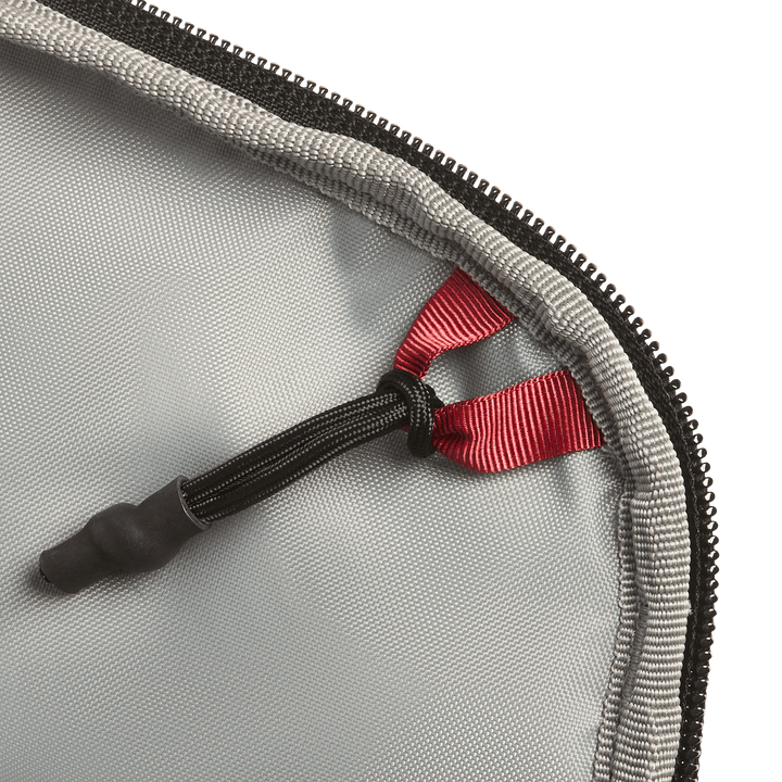 Close-up of the Vertx Everyday Fanny Pack 2.1 in gray, featuring a black zipper and a red ribbon loop attached to a black elastic cord with a rubber end, secured at the corner of the ballistic-panel compatible case.