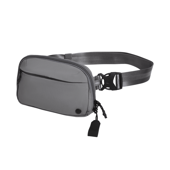 The Vertx Everyday Fanny Pack 2.1 by Vertx is a gray CCW fanny pack with a zippered front pocket, adjustable strap, plastic buckle, and a small black zipper pull attachment, shown on a plain white background.