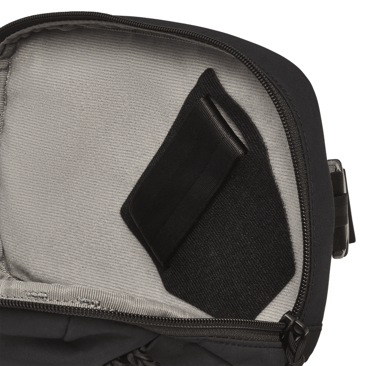 The Vertx Everyday Fanny Pack+ by Vertx is shown open, featuring a light gray interior lining and a small black Velcro-secured pocket on the inner lid that is compatible with ballistic panels.