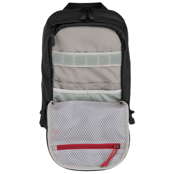 The Vertx Urban Ghost Sling, a product by Vertx, is open, showcasing its interior tailored for efficient everyday carry (EDC). It includes organized compartments with a mesh pocket that has a red zipper. The inside is ideal for streamlined storage and features a discreet CCW compartment to enhance its utility.