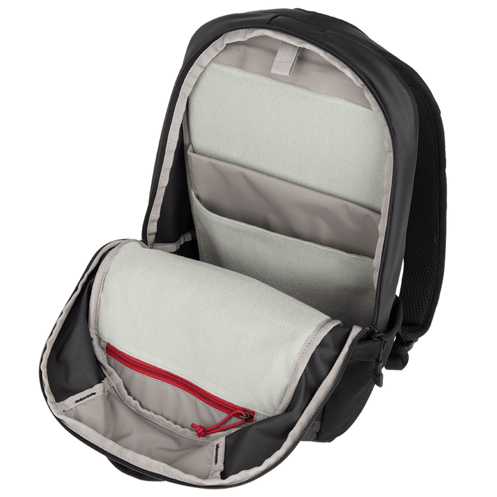 The Vertx Urban Ghost Pack by Vertx is an open black backpack with a roomy interior lined with light gray fabric. Made from durable ripstop fabric, it boasts multiple compartments, including a large main section and smaller pockets, one adorned with a red zipper, all beautifully displayed on a white background.