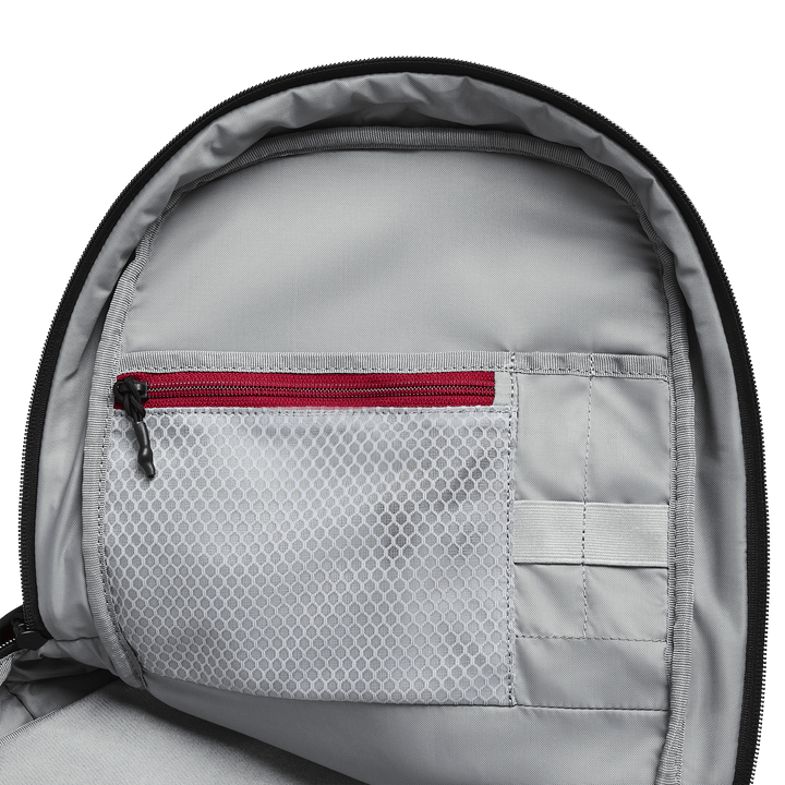 Close-up of the Vertx Any Day Backpack interior shows a mesh pocket with a red zipper, a solid gray pocket below, and two small open slots on the right—all in a ballistic-panel compatible design. Brand: Vertx.