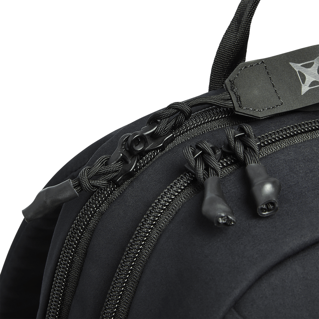 Close-up of Vertx Any Day Backpack zippers with paracord pulls and a black security lock securing the two zipper pulls; part of the handle and strap from Vertx are visible at the top.